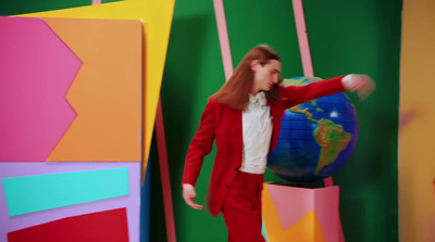 a woman in a red suit standing in front of a colorful wall