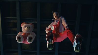 a woman in a red jumpsuit holding a teddy bear