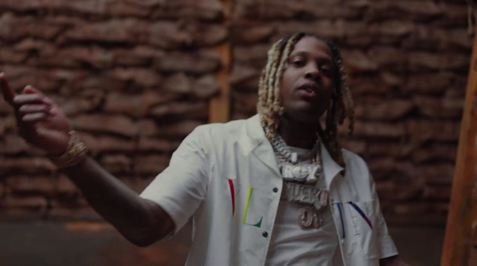 a man with dreadlocks standing in front of a brick wall