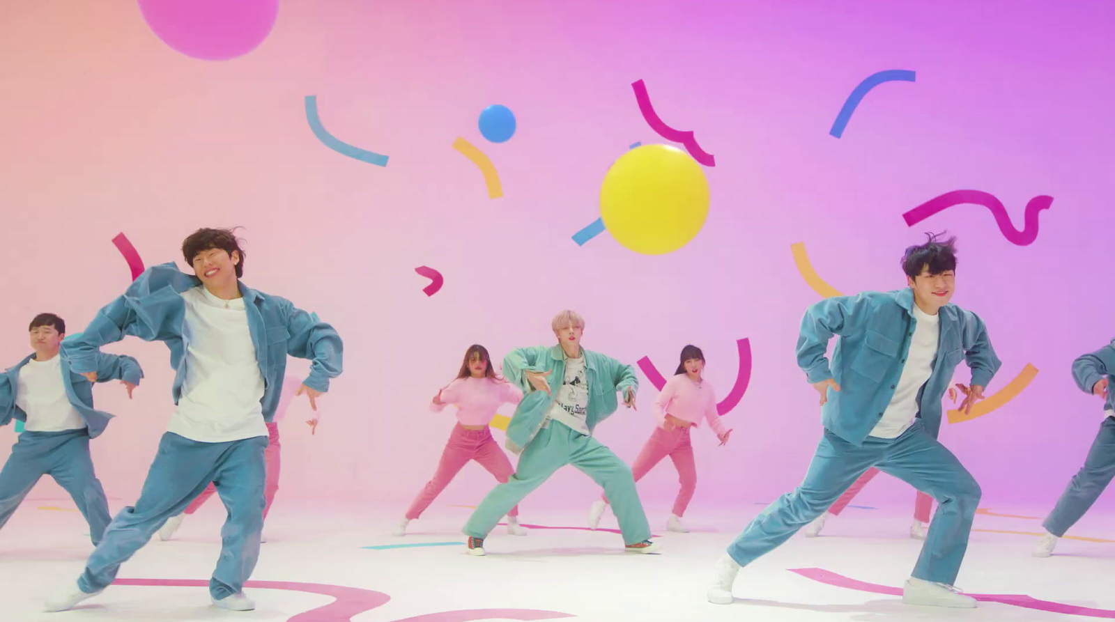 a group of young men dancing in front of a colorful background