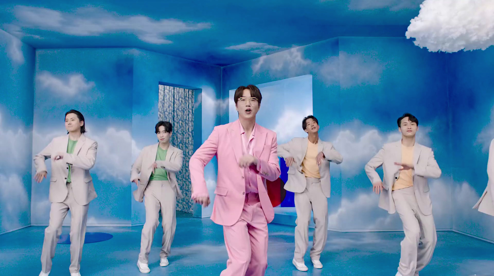 a man in a pink suit is dancing in front of a group of other men