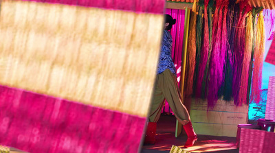 a woman walking past a colorful display of umbrellas