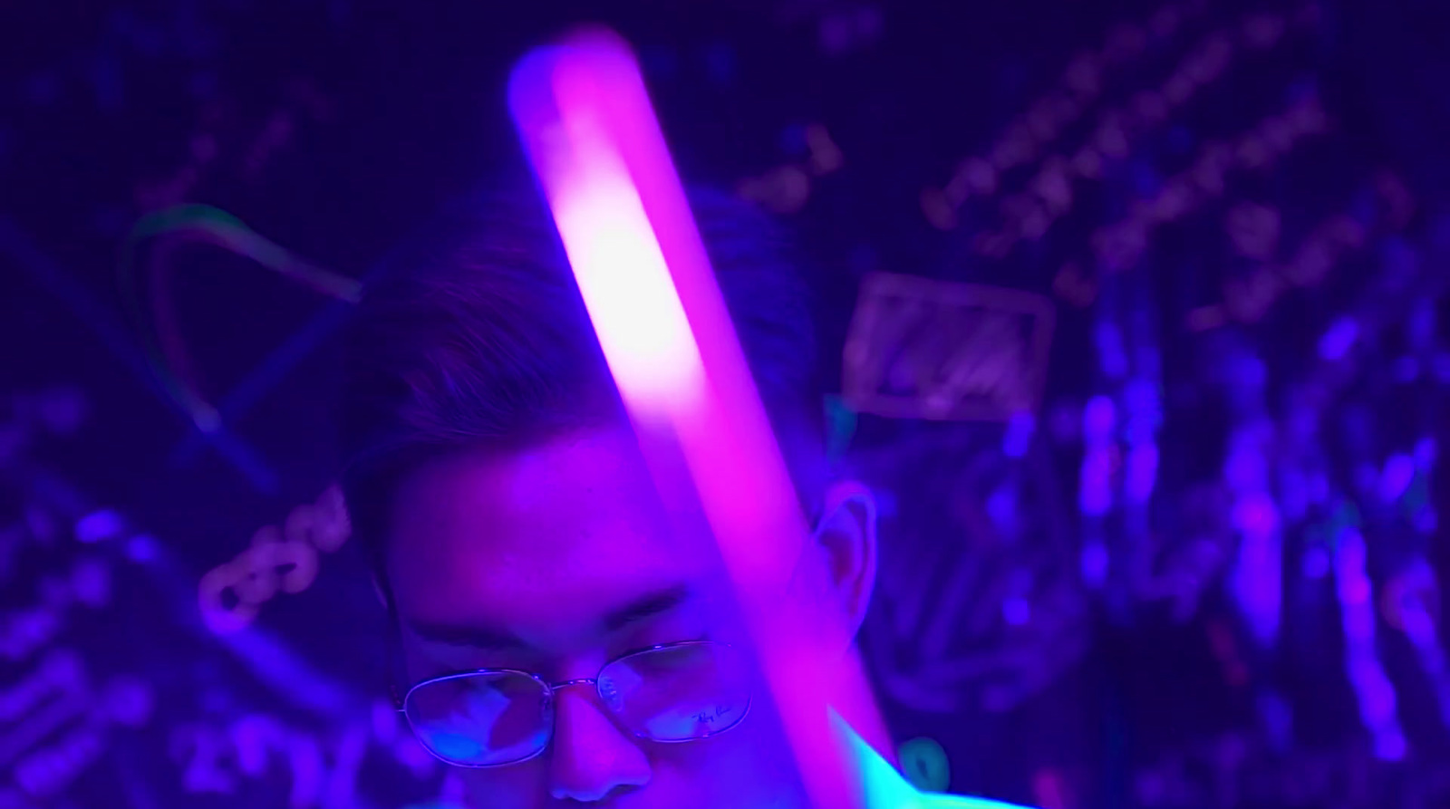 a man with glasses holding a neon stick