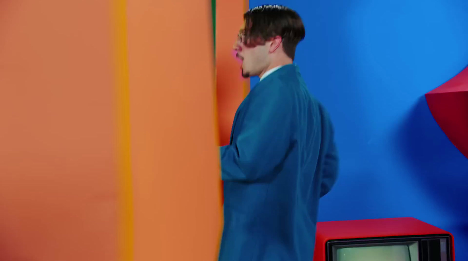 a man in a blue suit standing in front of a tv