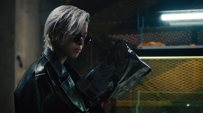 a woman in a black leather jacket holding a newspaper