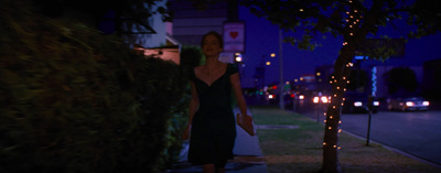 a woman walking down a sidewalk at night