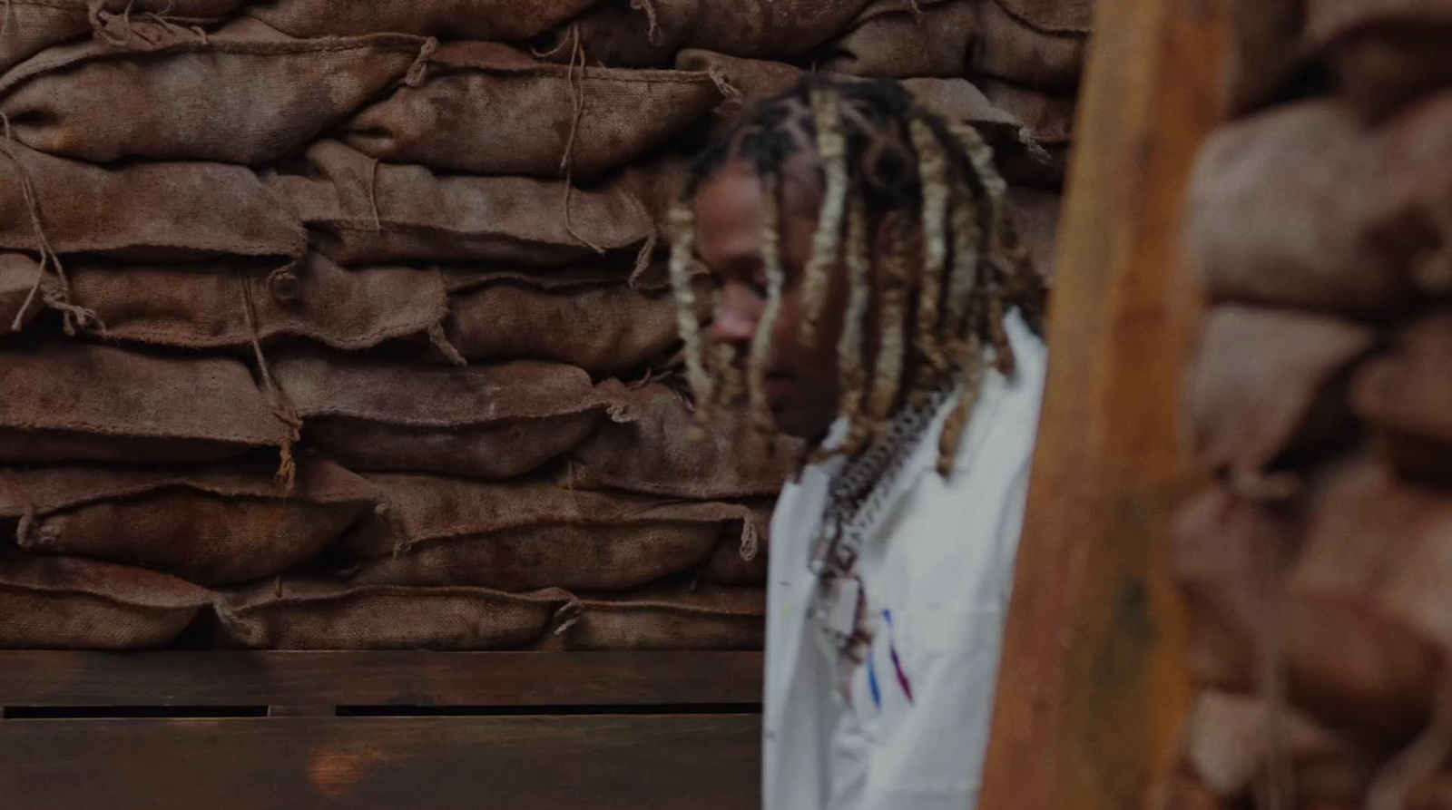 a man with dreadlocks standing in front of a pile of bags