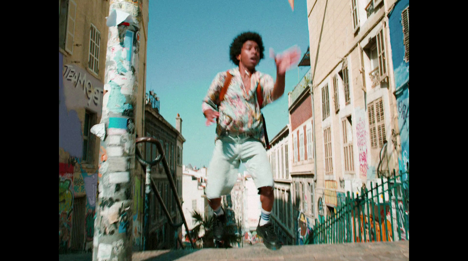 a man riding a skateboard down a street next to tall buildings