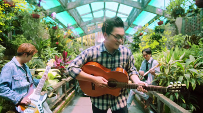 a man playing a guitar in a greenhouse