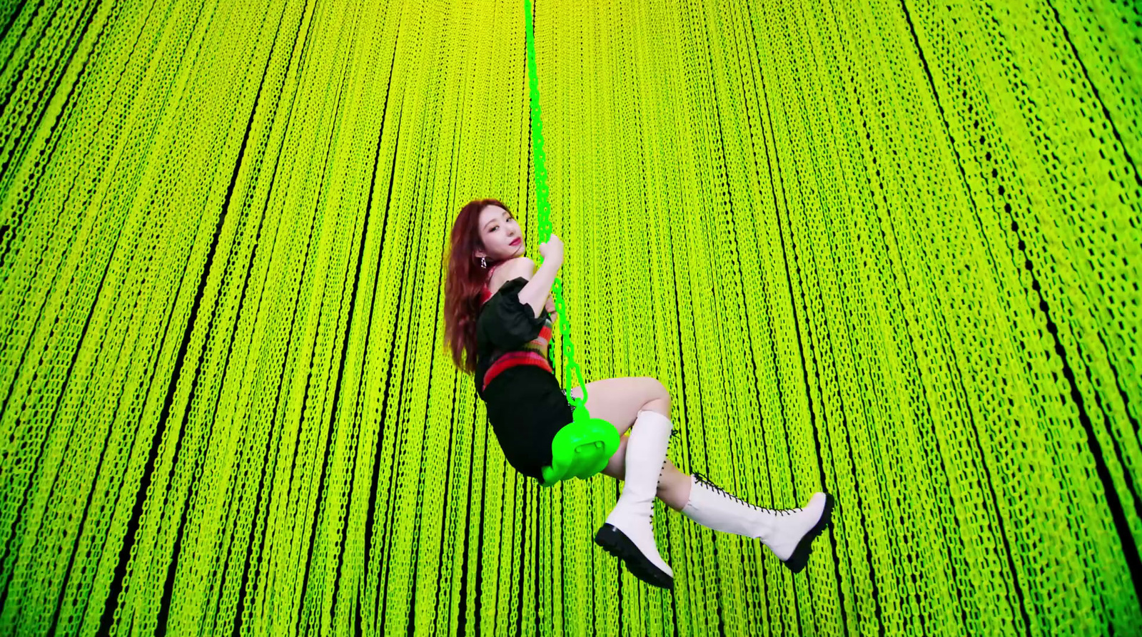 a woman in a black top and green skirt swinging on a rope