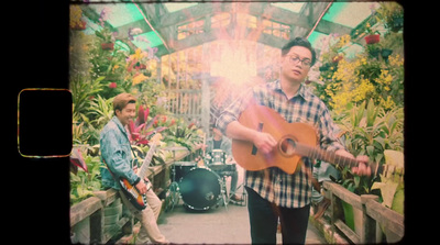 a man playing a guitar in a greenhouse