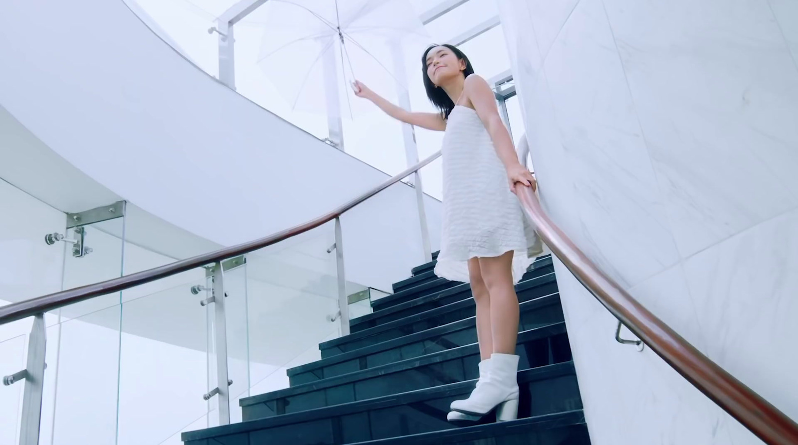 a woman in a white dress standing on a stair case