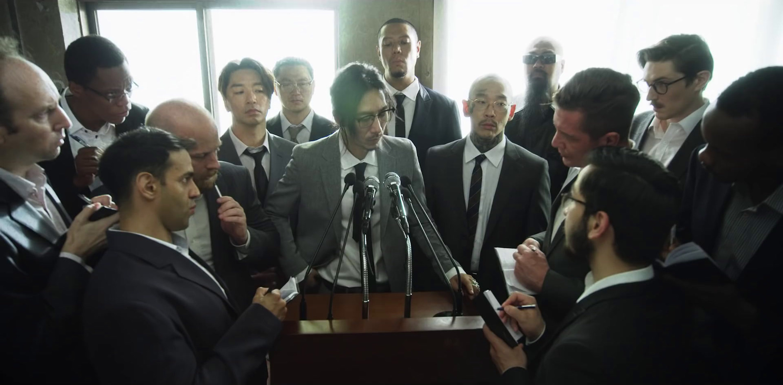 a group of men standing around each other in front of a microphone