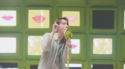 a man holding a yellow hair dryer in front of a green wall