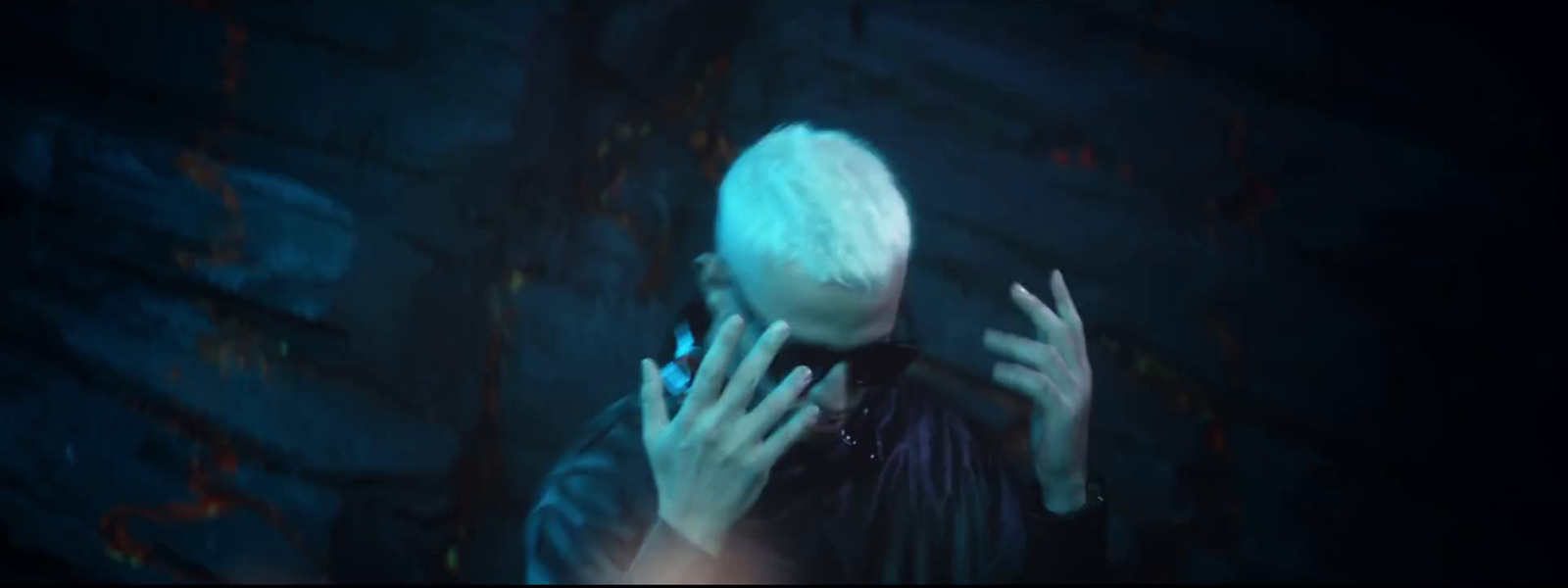 a man with white hair holding his hands up to his face