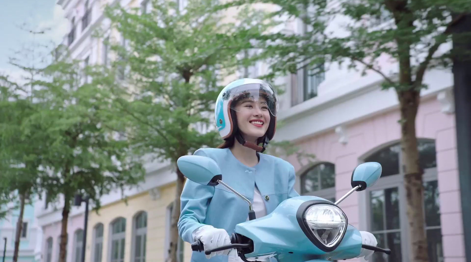 a woman wearing a helmet and riding a scooter