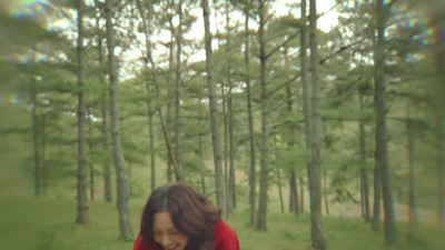 a woman in a red jacket walking through a forest