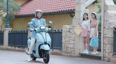 a woman riding on the back of a blue scooter