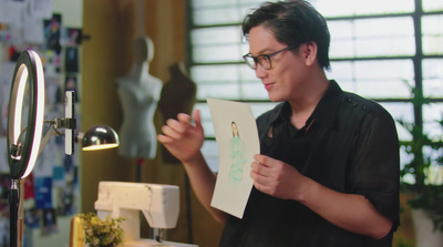 a man holding a piece of paper in front of a sewing machine