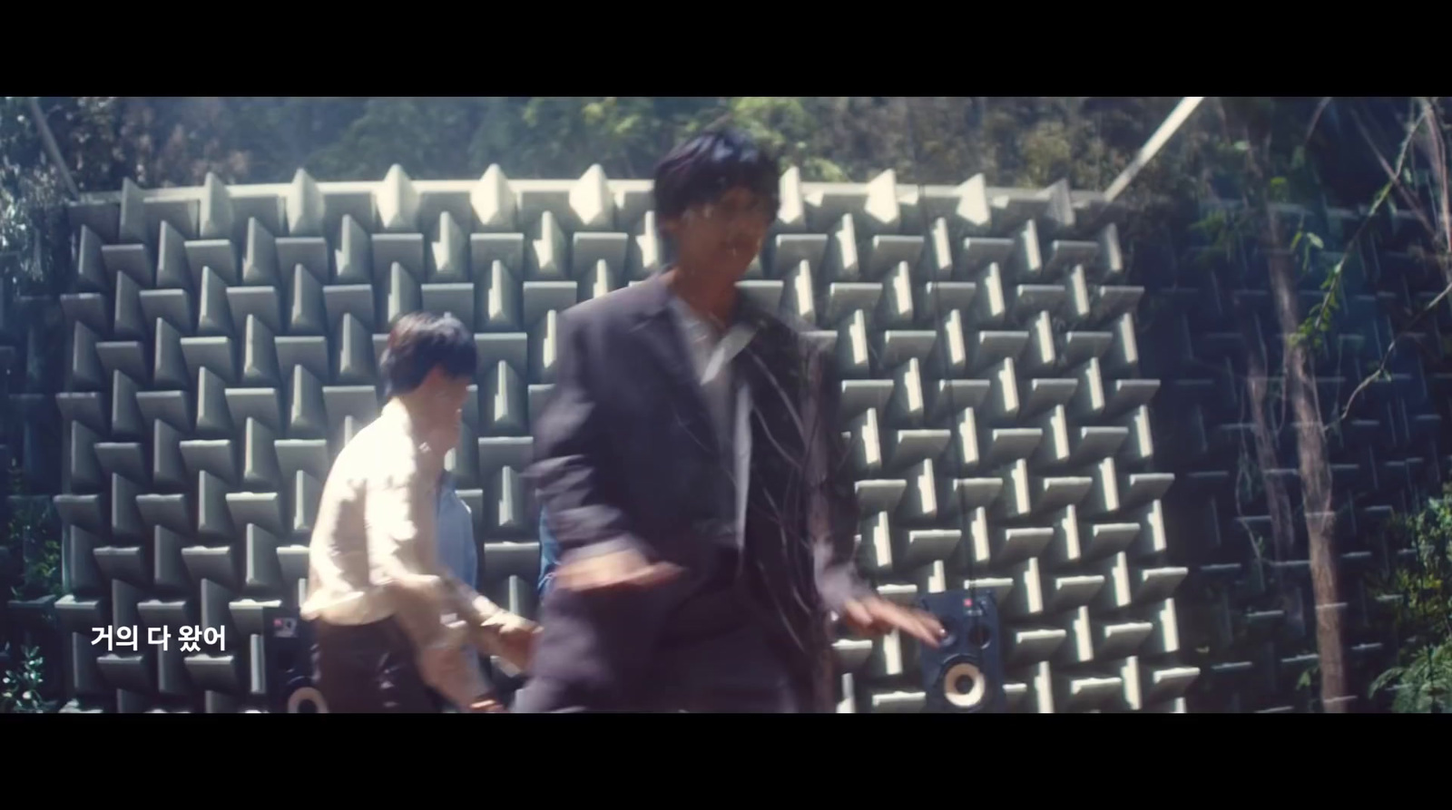 a man in a suit and tie walking by a wall