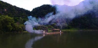 a boat floating on top of a lake surrounded by forest