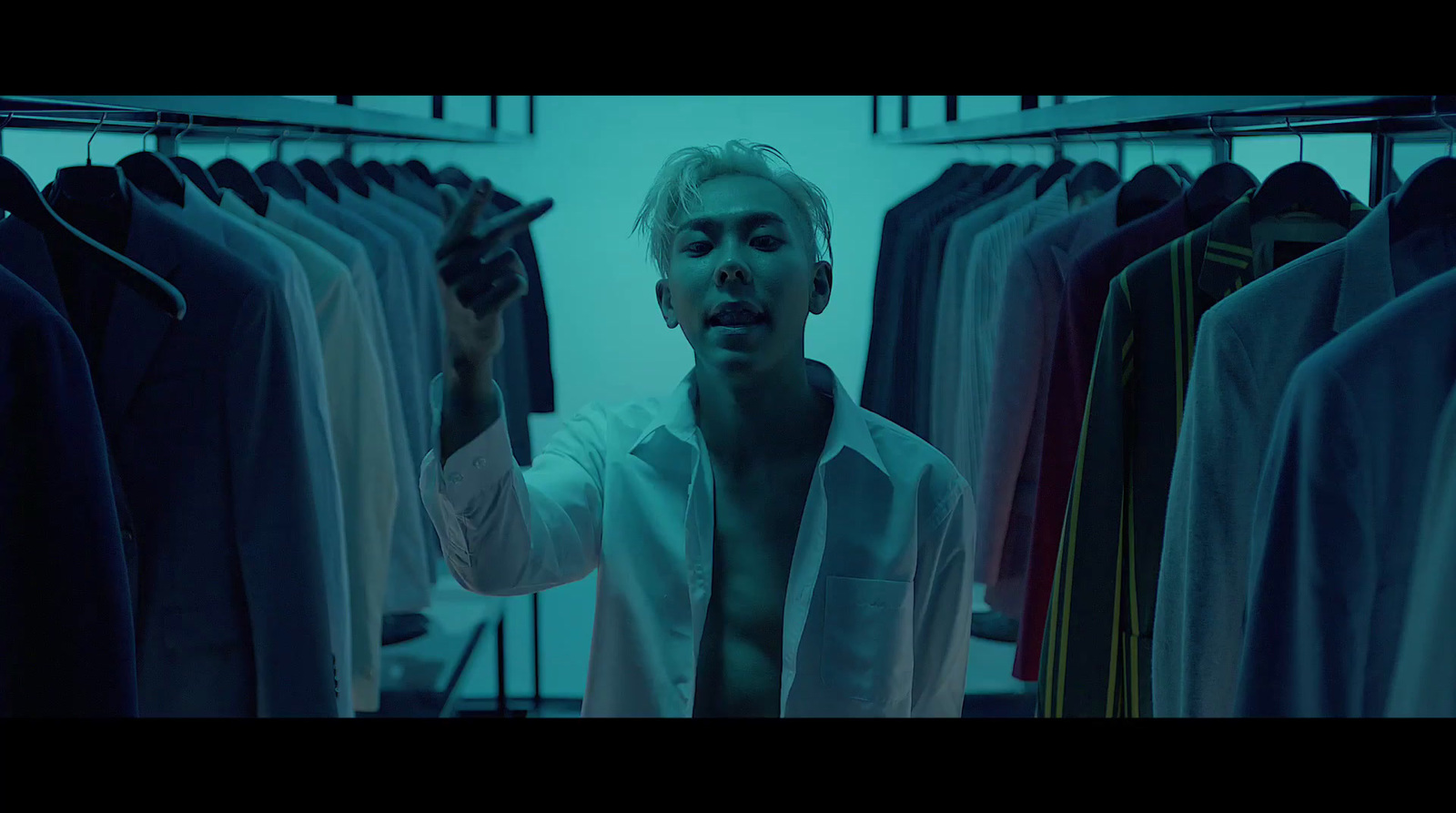 a man standing in front of a rack of shirts