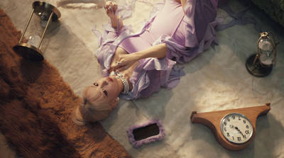 a woman in a purple dress laying on the floor next to a clock