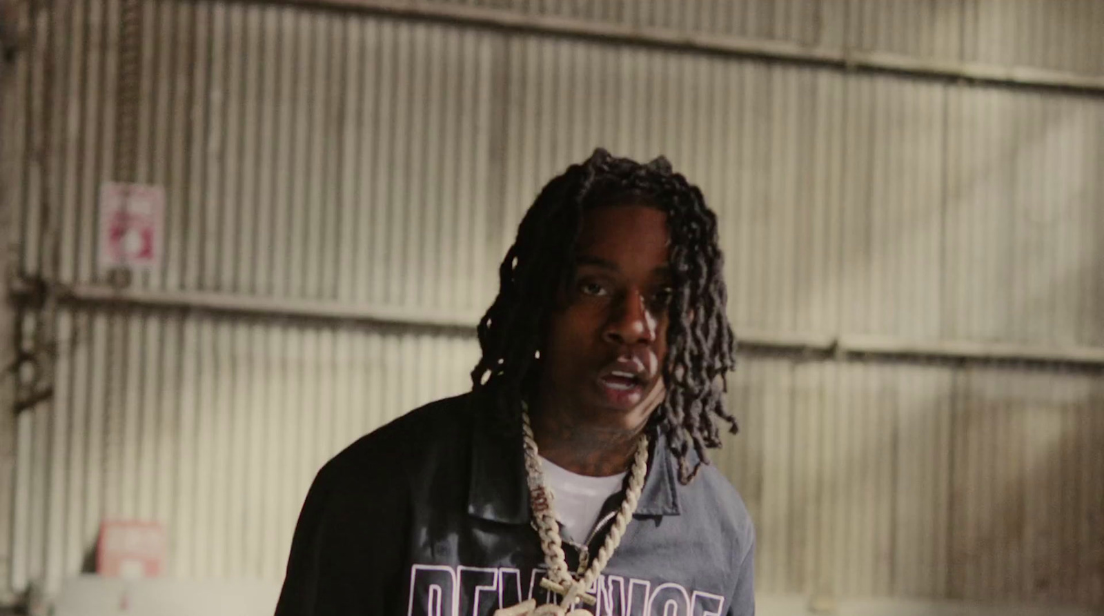 a man with dreadlocks standing in a garage