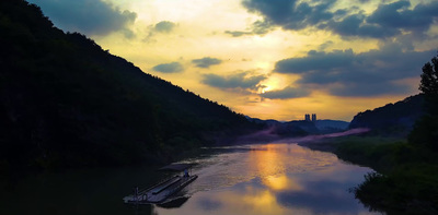 a boat floating on top of a river under a cloudy sky