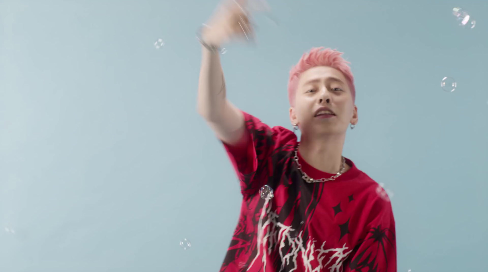 a man with pink hair is blowing bubbles