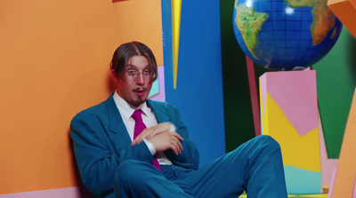 a man in a suit and tie sitting on a colorful wall