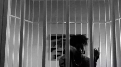 a person standing behind bars in a jail cell