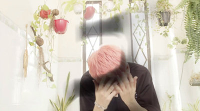 a person with pink hair sitting in front of a mirror