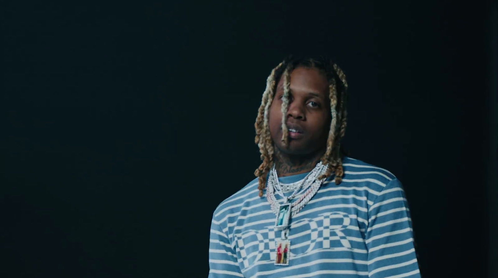 a man with dreadlocks standing in front of a black background