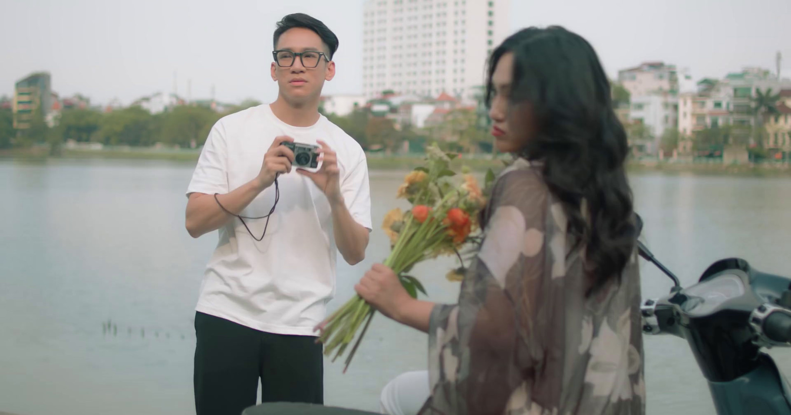 a man taking a picture of a woman holding flowers