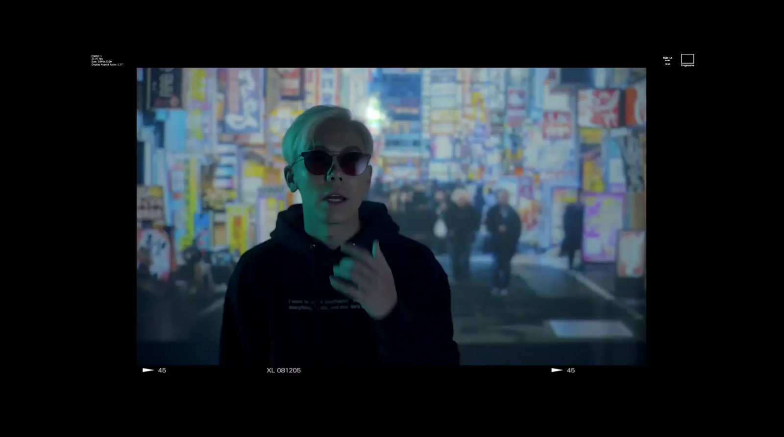 a man in a black jacket and sunglasses standing in front of a city street