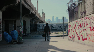 a man walking down a sidewalk next to a graffiti covered wall