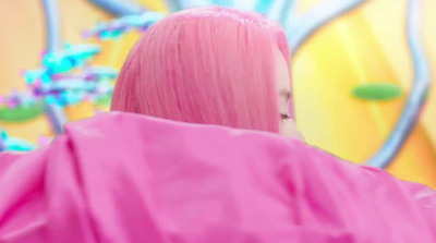 a woman with pink hair standing in front of a colorful background