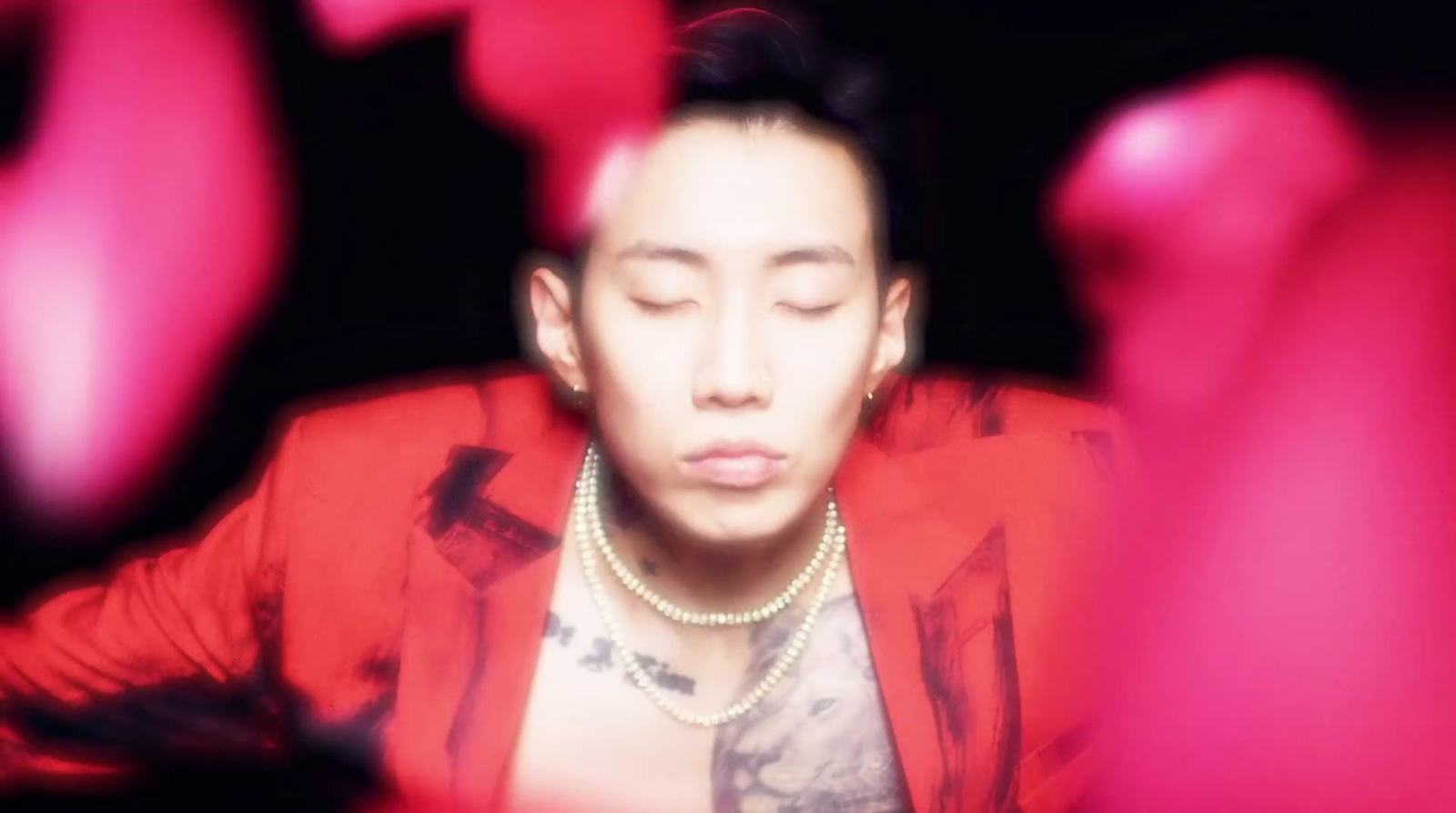 a man in a red jacket with a pearl necklace