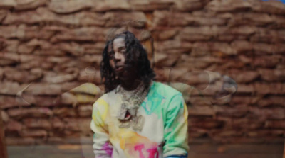 a man with dreadlocks standing in front of a brick wall