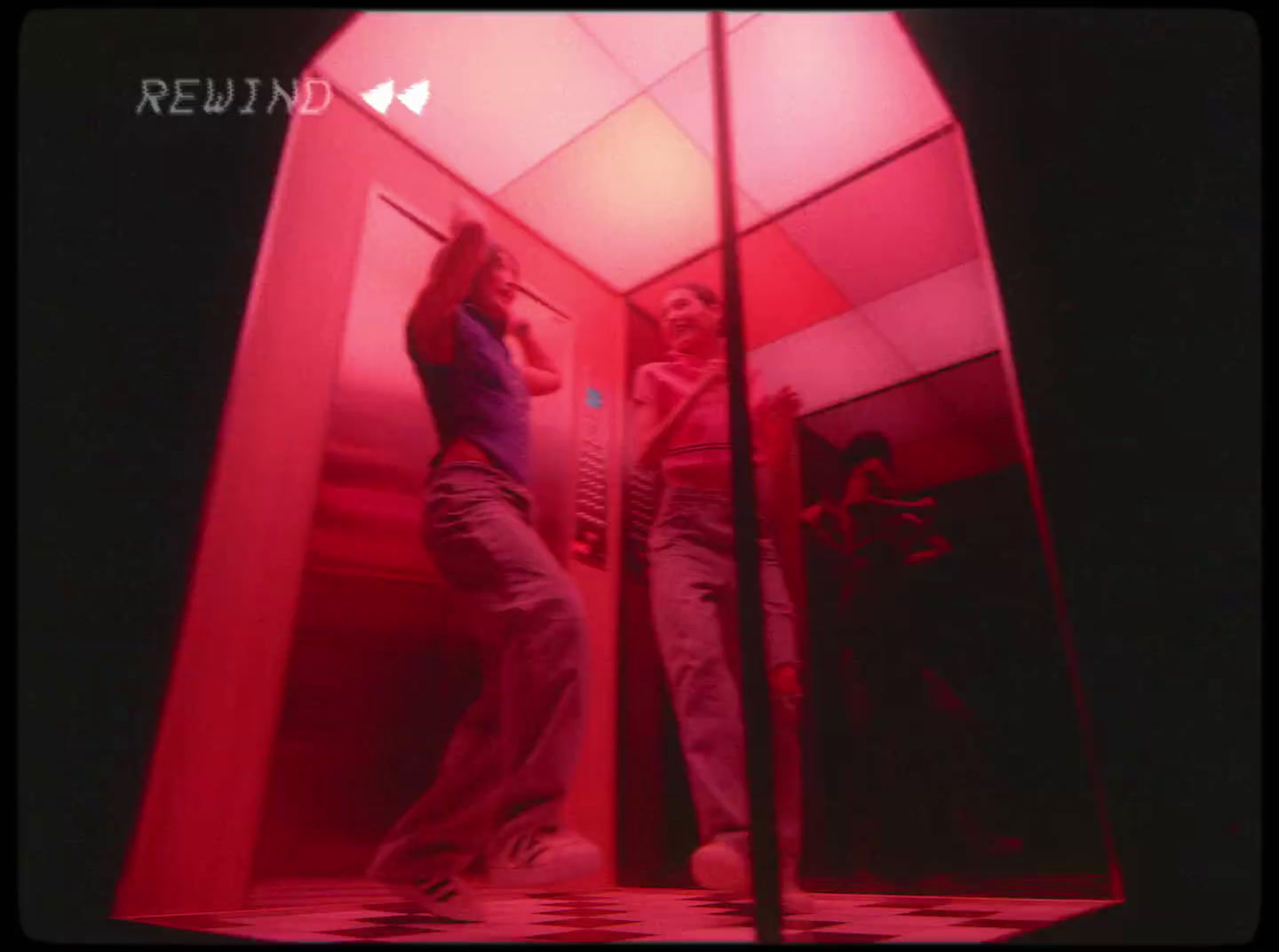 two people standing in a red room with mirrors