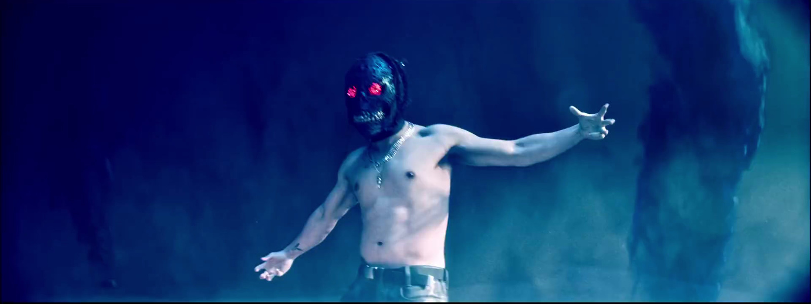 a shirtless man with a mask holding a pair of scissors