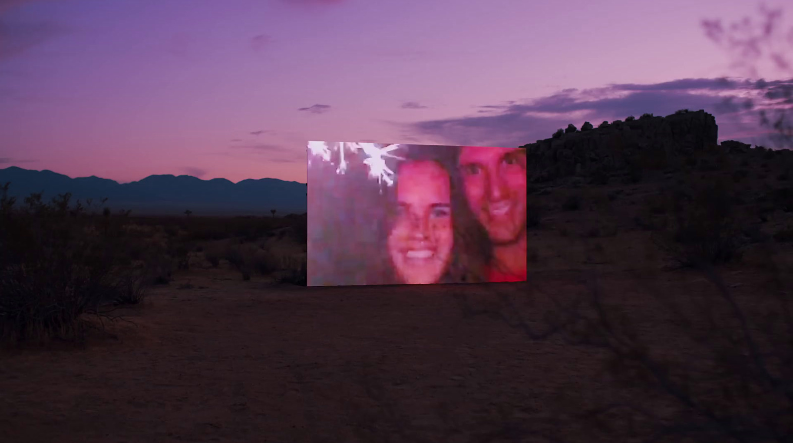 a picture of two people on a screen in the desert