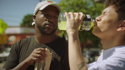 a man drinking from a bottle next to a woman