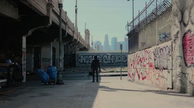 a man walking down a sidewalk next to a wall covered in graffiti