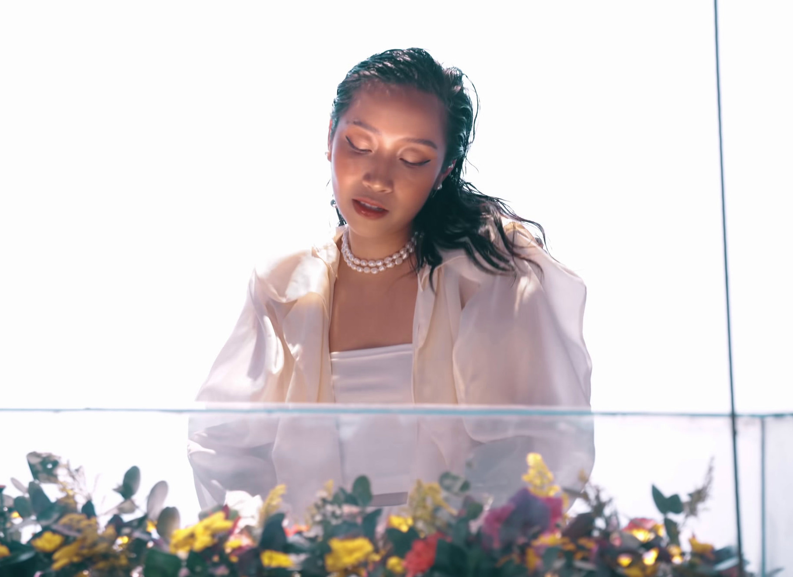 a woman wearing a pearl necklace standing at a podium