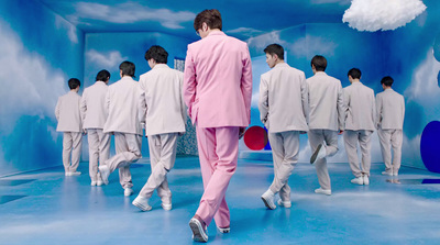 a man in a pink suit walking down a runway