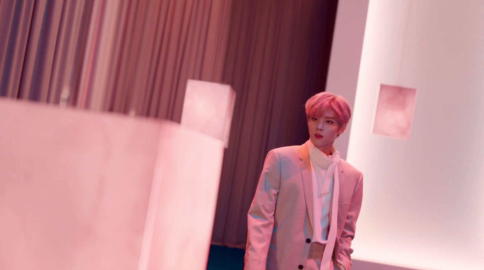 a man in a pink suit standing in a room