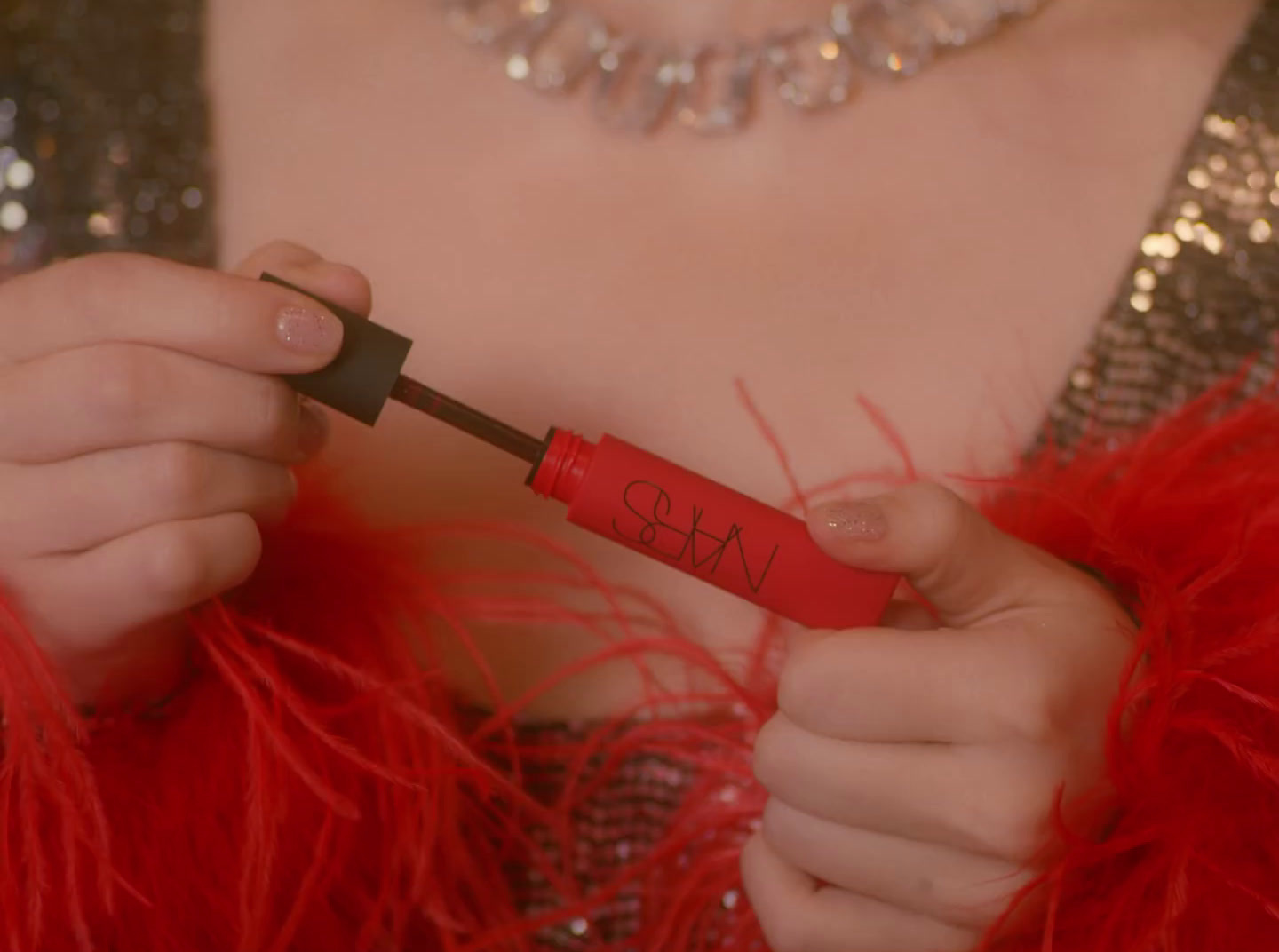 a close up of a person holding a red lipstick