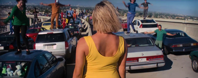 a woman in a yellow dress standing in a parking lot